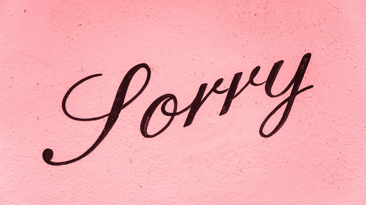 A sign saying sorry on a pink background.